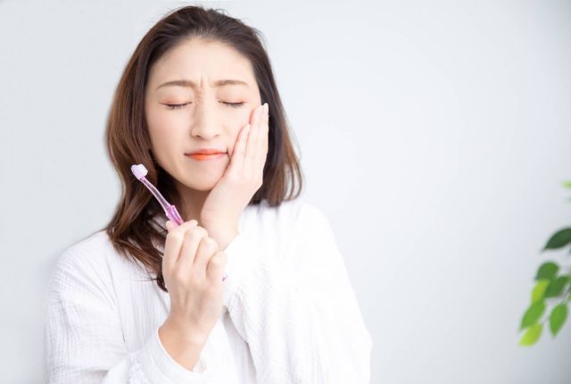 歯に痛みを感じている女性